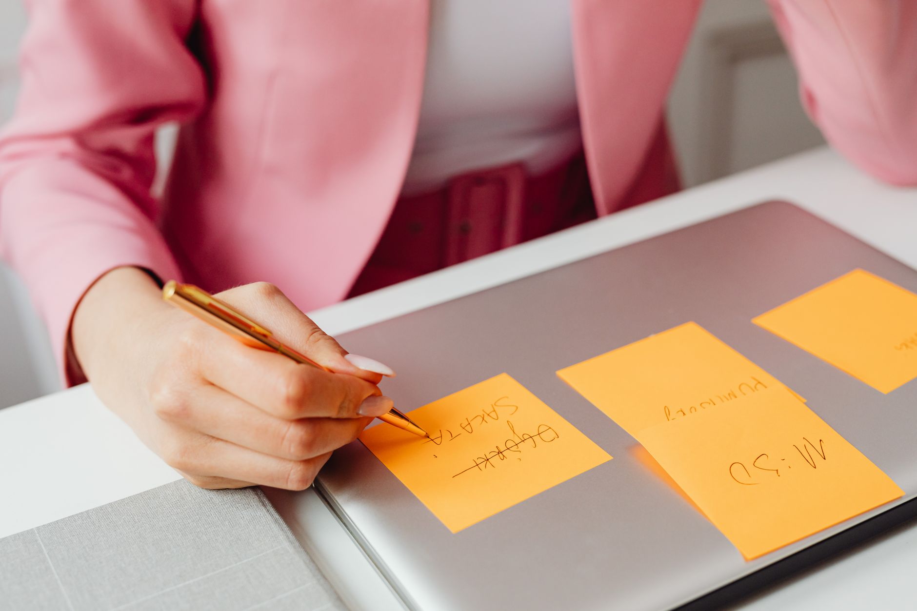Freelancer reviewing microtasks on a laptop with color-coded sticky notes for different projects