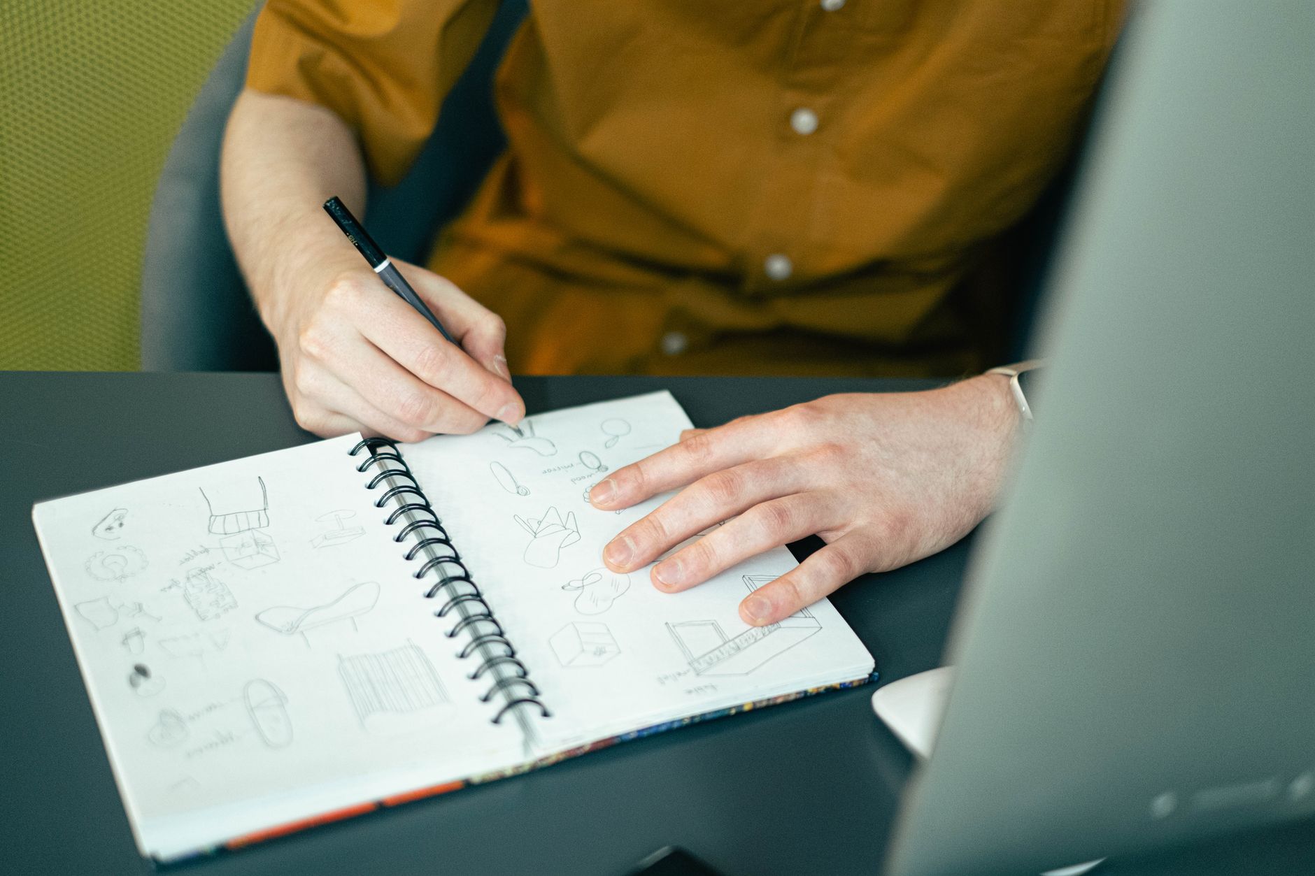 Designer sketching a logo in a notebook with annotations
